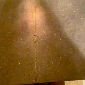 Women’s gold necklace with circle accent and a black honeycomb design on bottom